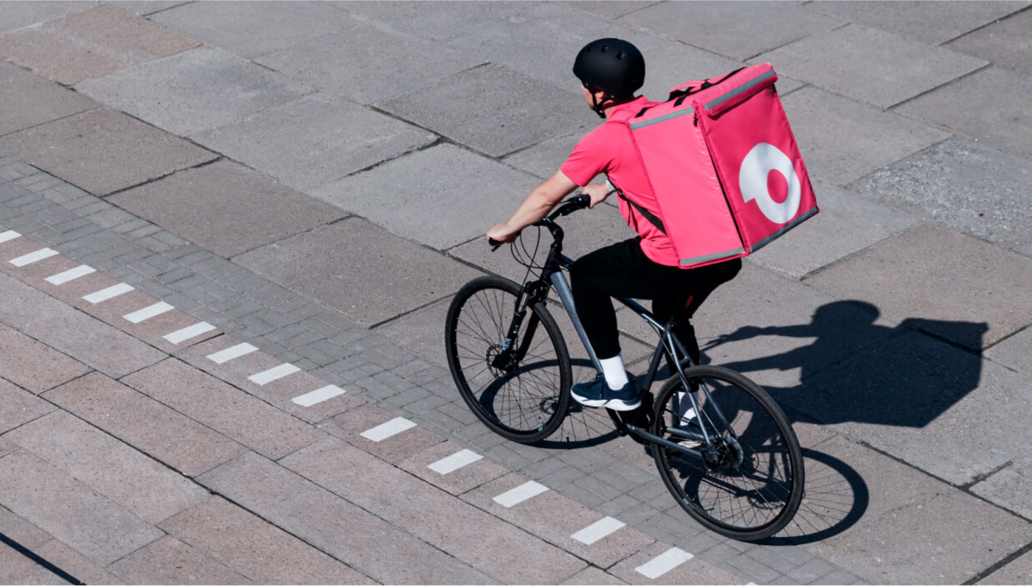 Courier riding a bicycle with a large pink delivery backpack.